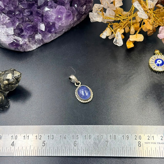 Oval blue gemstone locket pendant in 925 silver with textured halo and bail on a ruler