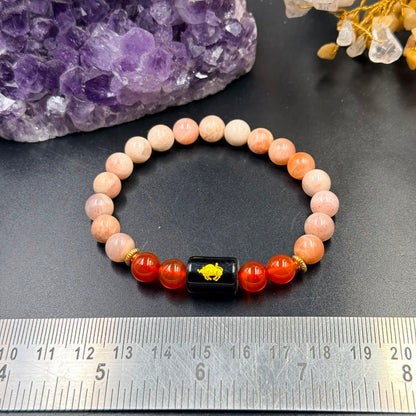 Taurus zodiac bracelet laid flat on dark surface with sunstone and carnelian beads and black bull centerpiece