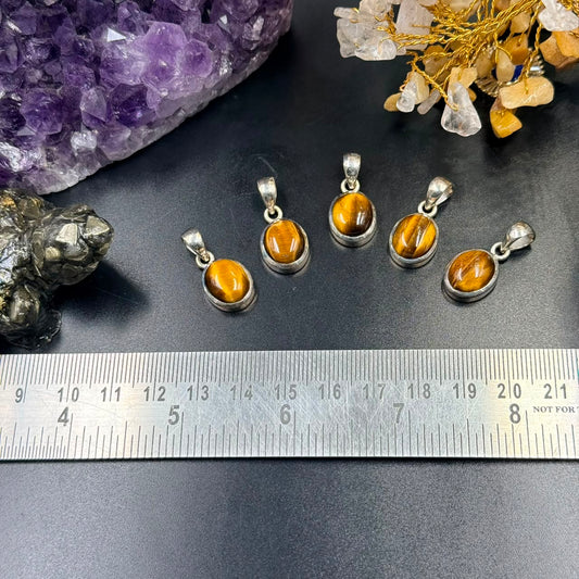 Tiger eye 925 silver locket charm with tiger eye cabochon on dark background