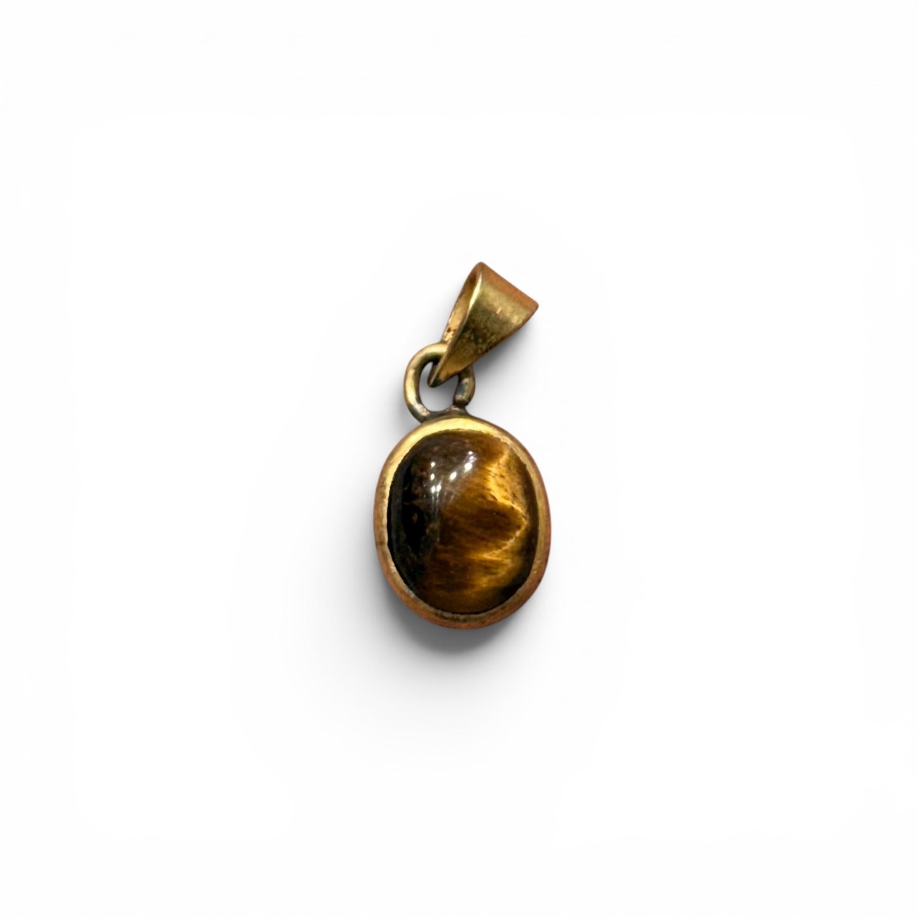 Tiger eye panchdhatu locket pendant with oval stone and gold-toned protective frame