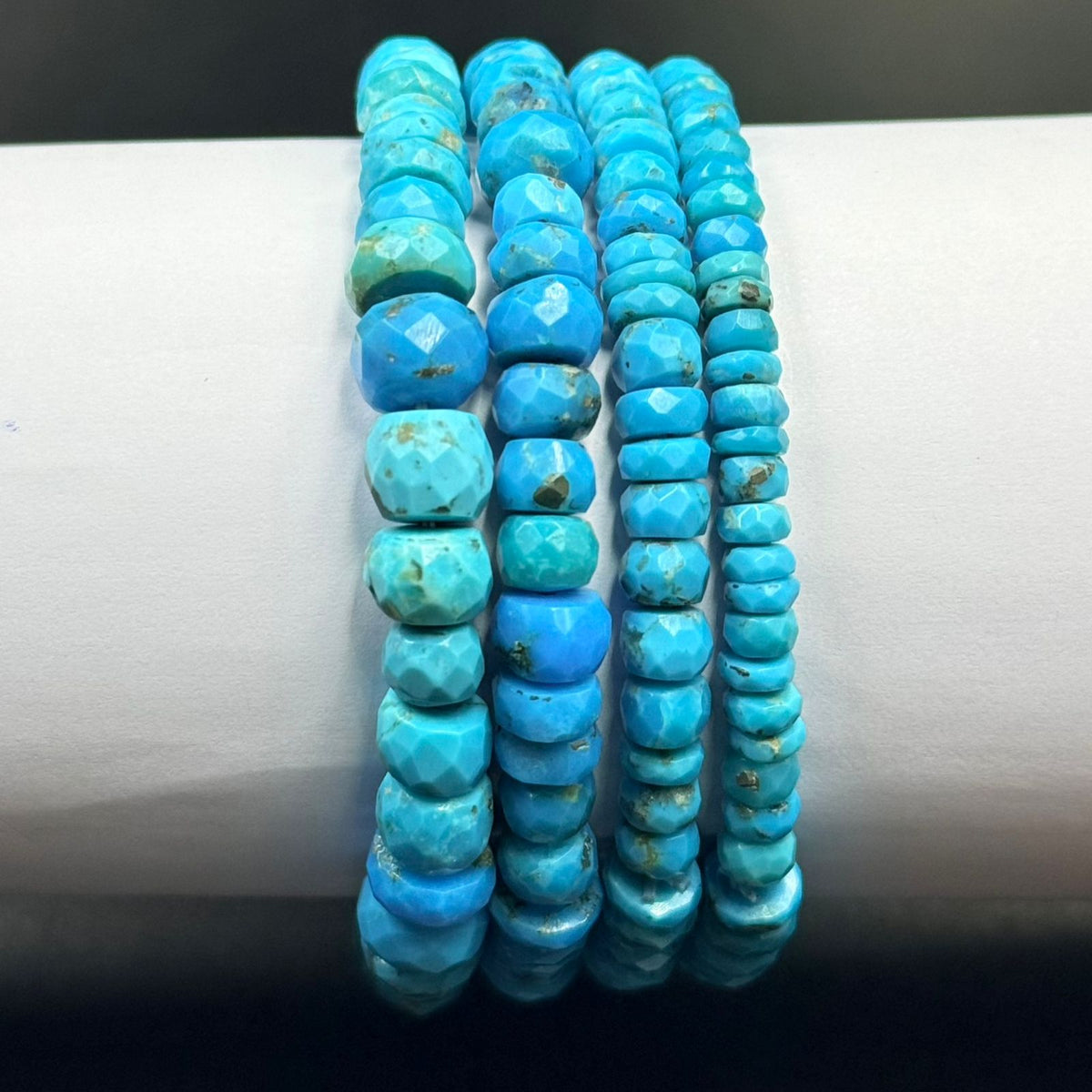 Close-up of turquoise flat rondelle beads with faceted texture and small natural marks