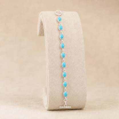 Turquoise oval-link 925 sterling silver nine-stone bracelet shown on display stand