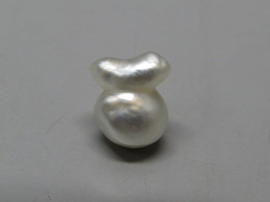 Cultured pearl keshi (moti) with smooth white luster, close-up on neutral background