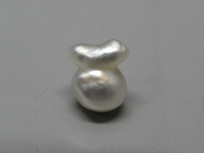 Cultured pearl keshi (moti) with smooth white luster, close-up on neutral background