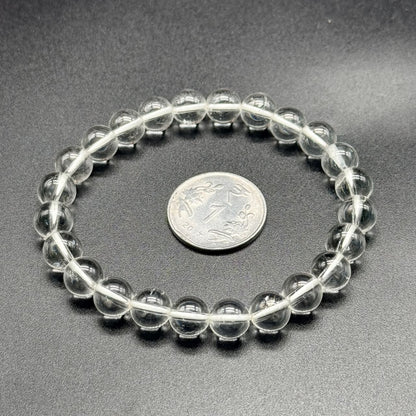 White topaz beaded bracelet close-up showing round clear stones on gray background with coin