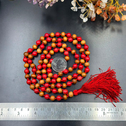 Wood and coral Jaap mala bead necklace with red tassel, laid out on dark background