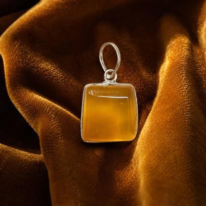 Yellow onyx pendant with silver frame and loop bail on golden velvet fabric
